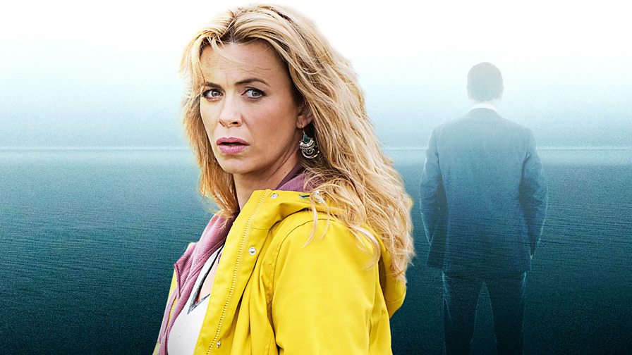 A woman looking pensively towards the camera. She is wearing a yellow coat, and her long hair falls down her back. Behind is a silhouette of a man facing away, and the sea is in the background.